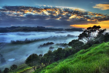 Amanecer con niebla baja sobre un valle verde