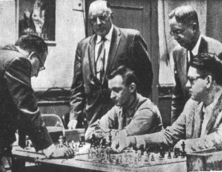 Partida correspondiente a unas simultneas (foto en blanco y negro). Se ve al jugador que da la sesin, a dos jugadores sentados y otros dos observando (uno de ellos es Ohman)
