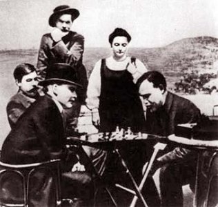 Fotografa con dos hombre jugando al ajedrez (uno de ellos Gorky) y una mujer y dos hombres observando (uno de ellos Lenin)